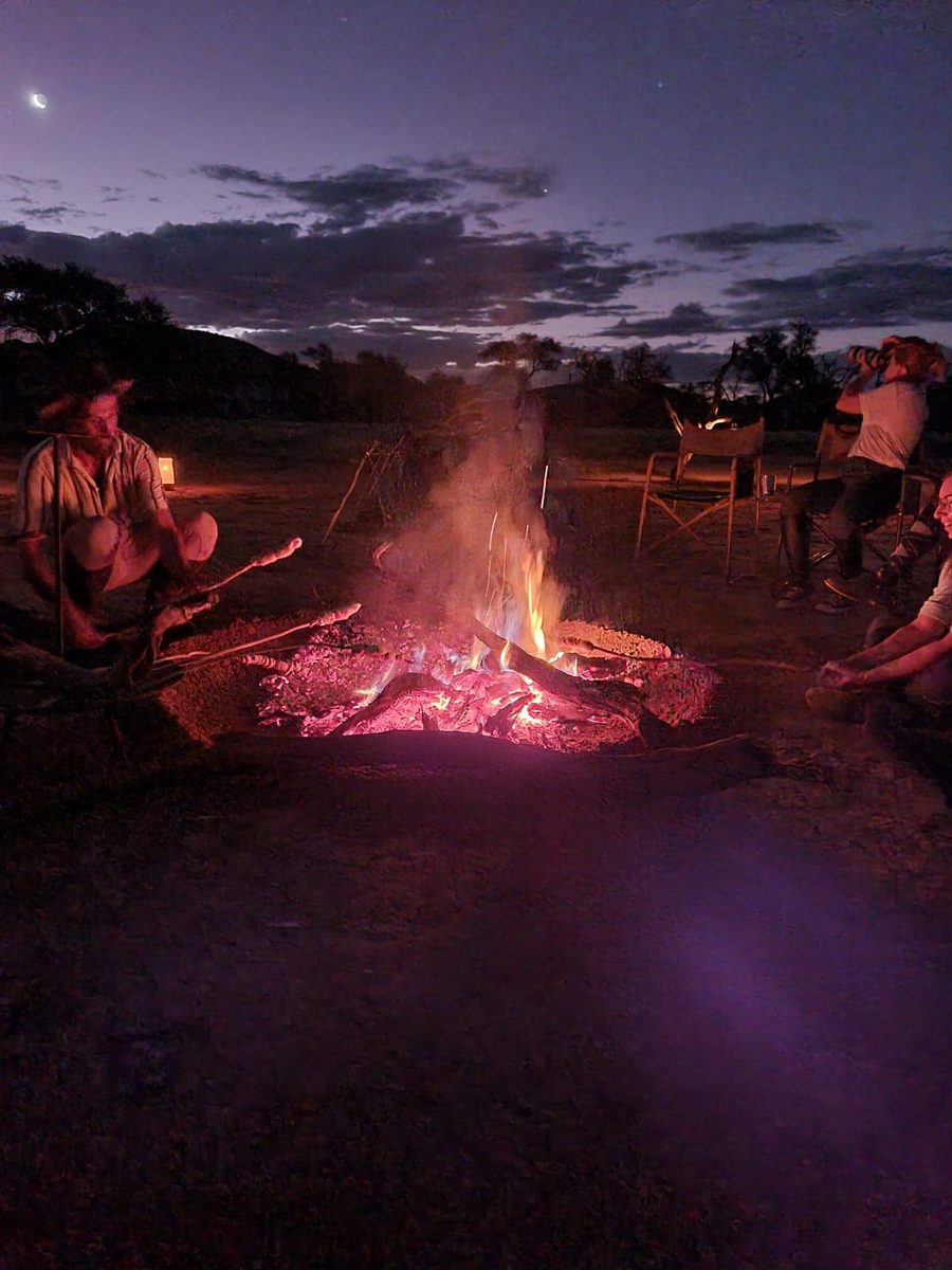 Guests around the fire under a crescent moon