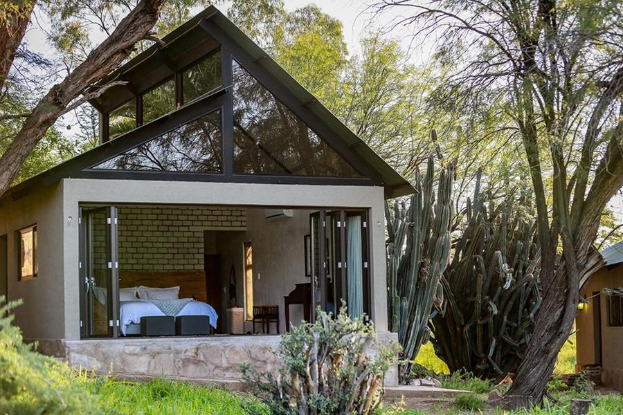 A cottage with its glass front folded open under the trees