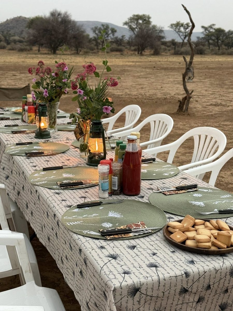 A table in the bush with flowers and lanterns